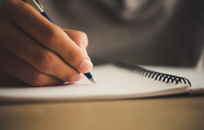 Man hand with pen writing on notebook.
